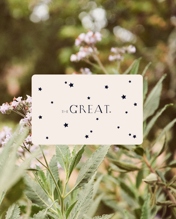 A cream-colored Rise.ai Gift Card with black stars and "THE GREAT." text rests on a blurred leafy backdrop—an ideal choice for any thoughtful gift recipient.