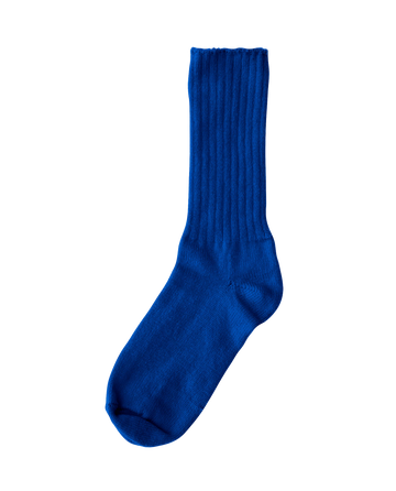 A bright blue cashmere sock by THE GREAT. HOL 22 D2 CASHMERE stands out against a plain white background.