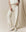Someone wearing The Wide Leg Cropped Sweatpant in Washed White by THE GREAT. CORE KNITS and a sleeveless top, paired with white high-top sneakers, stands on a neutral fabric backdrop.