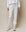 A person in THE GREAT. HOL 24 KNITS' The Stadium Sweatpant in True White, paired with a white sweatshirt and sneakers, captures the essence of vintage athletic wear against a neutral background.