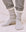 A person stands on a soft beige surface wearing THE GREAT. SP25 SWEATSHIRT SOCKS in Heather Grey, paired with a cozy gray sweatshirt and matching sweatpants.