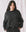 A woman with long dark hair, dressed in The Slouch Sweatshirt by THE GREAT. CORE KNITS in an almost black shade, stands against a light background, exhibiting an extra slouch paired with pants.